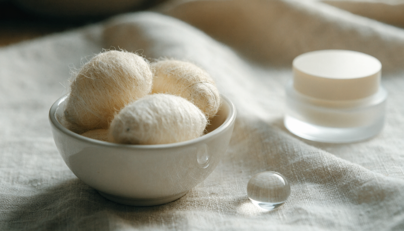 Cocons de soie naturels dans un bol, ambiance skincare douce et minimaliste